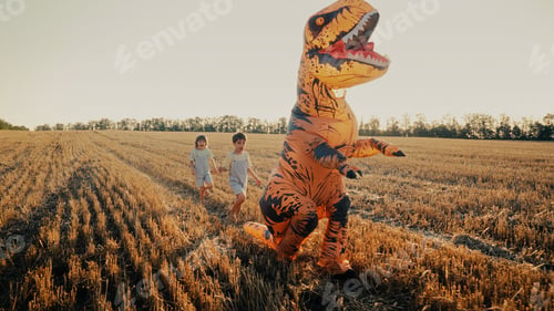 Preview: Inflatable Dinosaur T-Rex Is Chased, Running From Little Kids Boys In Field.