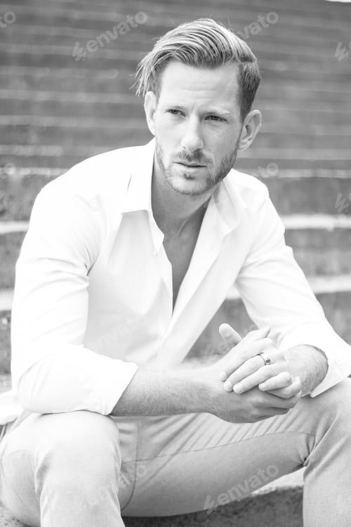 Preview: Vertical grayscale shot of the handsome young man posing outdoors.