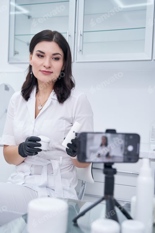 Preview: Smiling beauty master posing on camera of smartphone