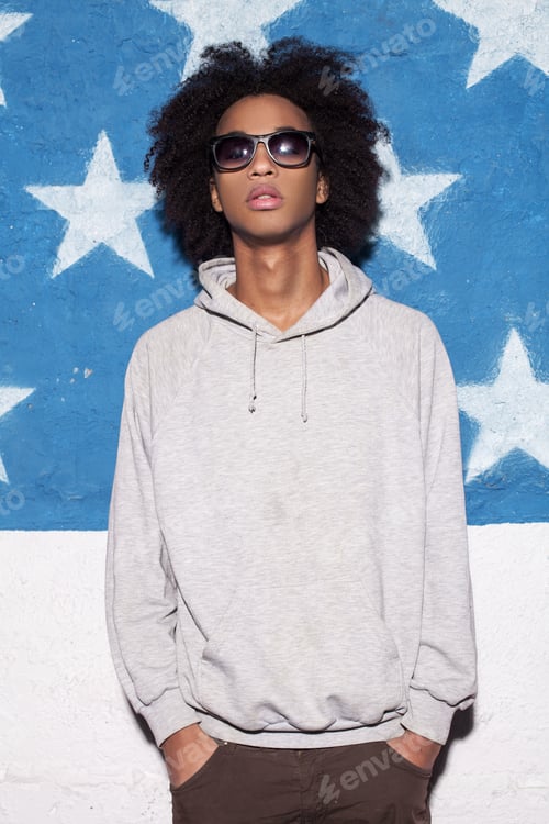 Preview: Cool and casual. Young African man in sunglasses standing against American flag
