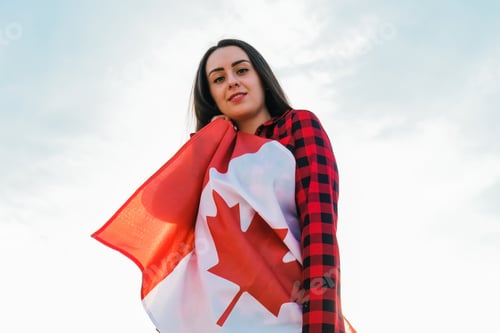 Preview: Young millennial brunette woman holding The National Flag of Canada. Canadian Flag or the Maple Leaf