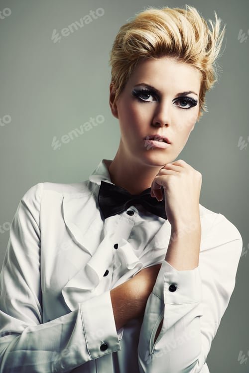 Preview: Studio shot of a beautiful young woman wearing a shirt and bow tie against a gray background