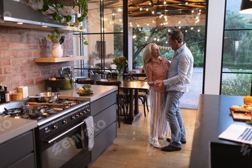 Preview: Senior Caucasian couple dancing in the kitchen during coronavirus covid19 pandemic