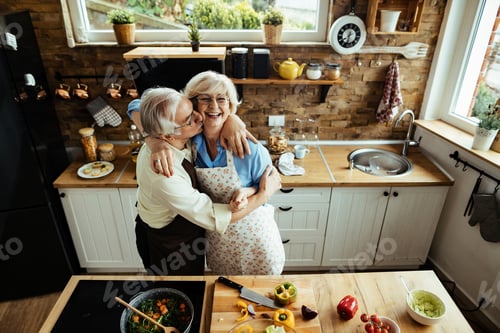 Preview: Embraced mature couple having fun while preparing food in the kitchen.