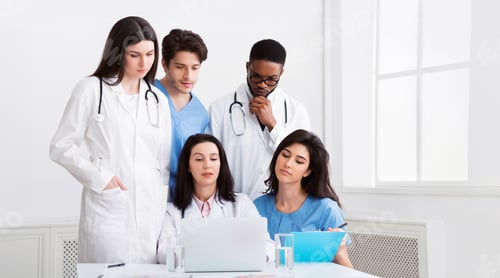 Preview: Multiracial doctors looking at laptop, working together in clinic