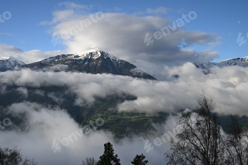 Preview: Fluffy clouds over a mountain range with snow-covered peaks