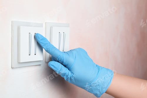 Preview: Woman in protective gloves pressing button of light switch indoors, closeup
