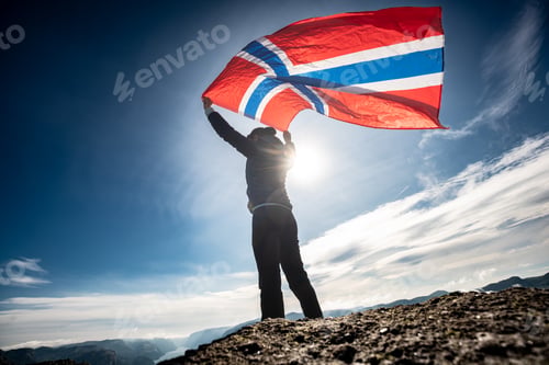 Preview: Woman with a waving flag of Norway on the background of nature