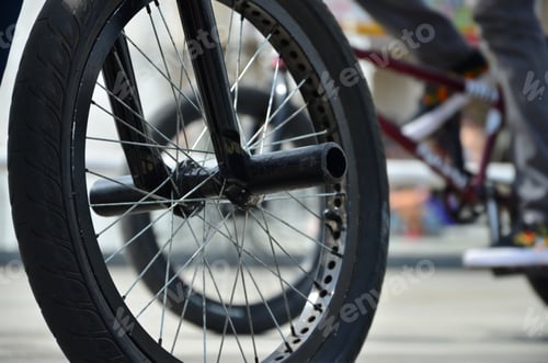 Preview: A BMX bike wheel against the backdrop of a blurred street with cycling riders