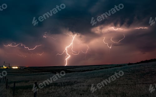 Preview: Lightning streaks across a twilight sky over a rural landscape.