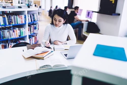 Preview: Focused student reading textbook in library