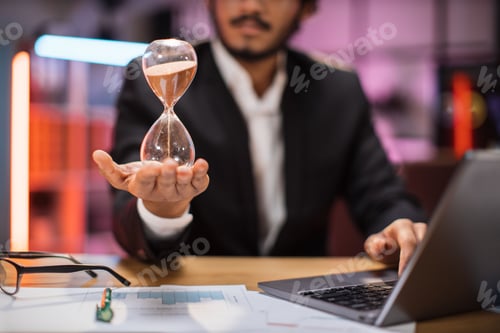 Preview: Focus on hand of smiling confident businessman holding hourglass