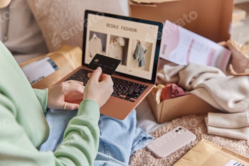 Preview: Cropped image of unrecognizable woman holds credit card and uses laptop computer makes shopping