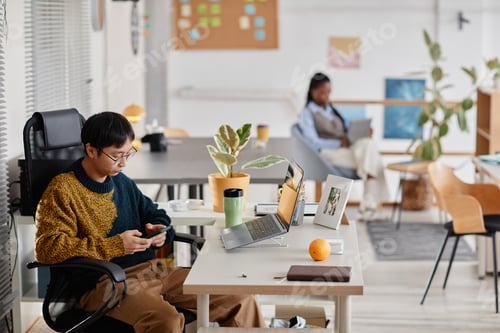 Preview: Young Professional Using Smartphone in Modern Office Setting