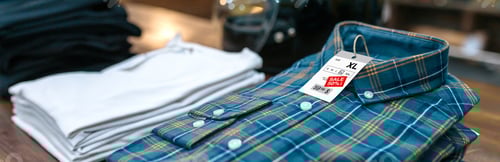 Preview: Detail of label with promotion price over a blue plaid shirt on shop with industrial style