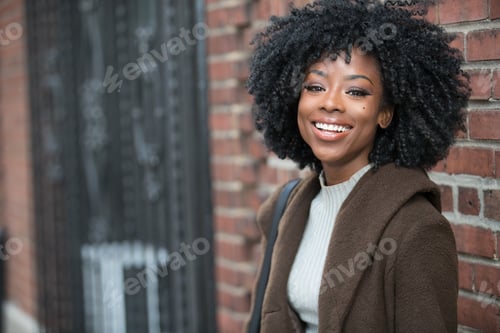 Preview: Happy African American woman near brick wall outside