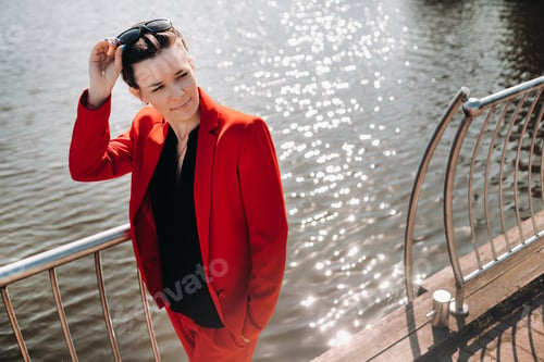 Preview: A girl in a red suit stands on a pier near the lake