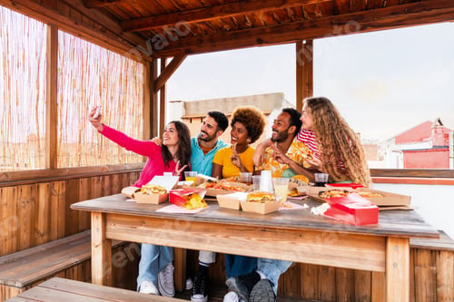 Preview: Multiethnic group of friends having dinner barbecue party on rooftop at home