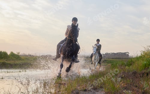 Preview: Shot of two young women riding their horses outside on a field