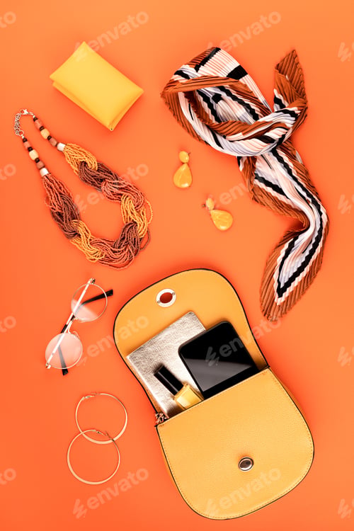 Preview: Flat lay with woman fashion accessories in yellow color over orange yellow textured background
