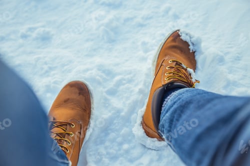 Preview: Man legs in winter boots on snow near mountains