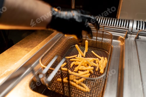 Preview: professional cuisine in the hotel restaurant the cook throws potatoes into the deep fryer