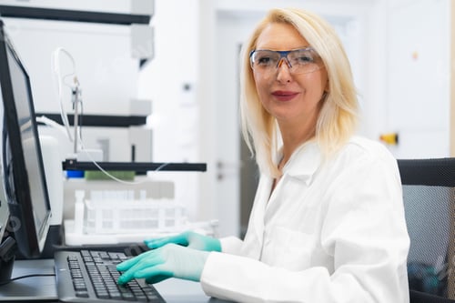 Preview: Female scientist working on computer in front of HPLC