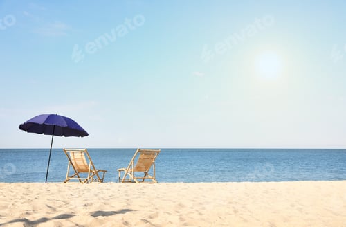 Preview: Empty wooden sunbeds and umbrella on sandy shore. Beach accessories