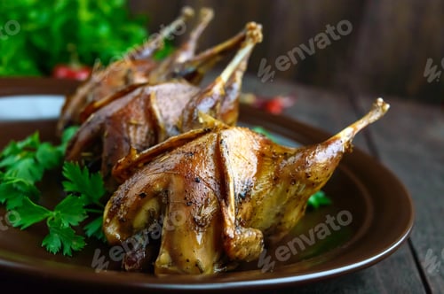 Preview: Roasted quail on a spit. Serving on a ceramic plate with greens. Close-up. Holiday menu.