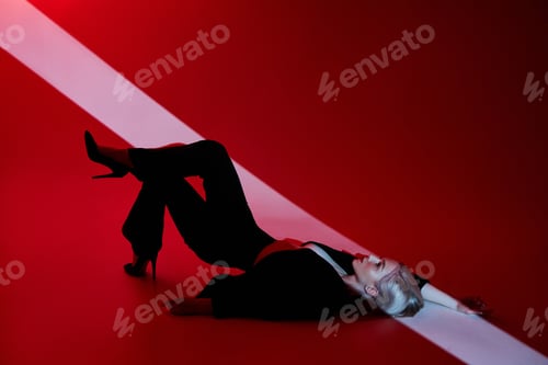 Preview: Woman lies on red background with ray of light on face. Sexy nude and confident