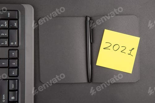 Preview: top view black notebook pen keyboard written on note paper on dark background