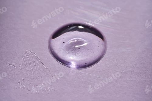 Preview: A drop of oil serum on a purple background with beautiful highlights.
