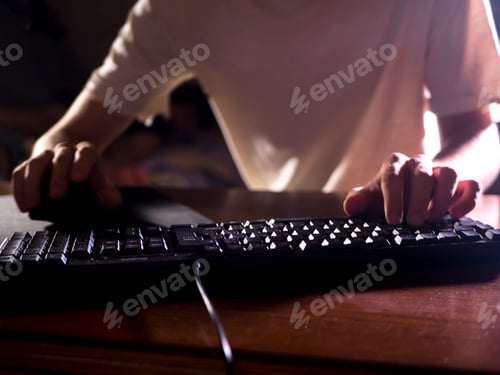 Preview: close up gamer hands on the keyboard playing video games in the night