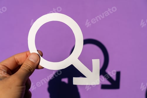 Preview: Closeup of a person holding the male symbol on a purple background