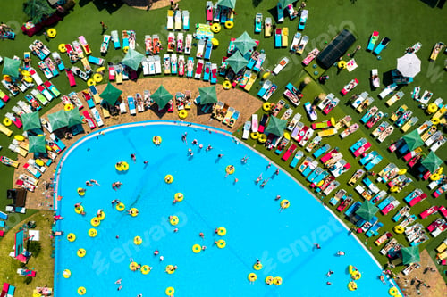 Preview: Top view of people relaxing in the pool on yellow inflatable circles and sun beds on the beach