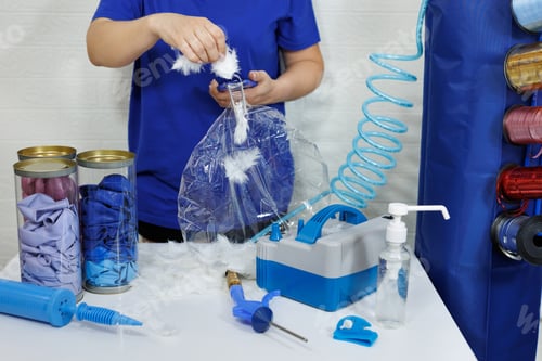 Preview: A female aerodesigner adds white feathers to a transparent balloon.