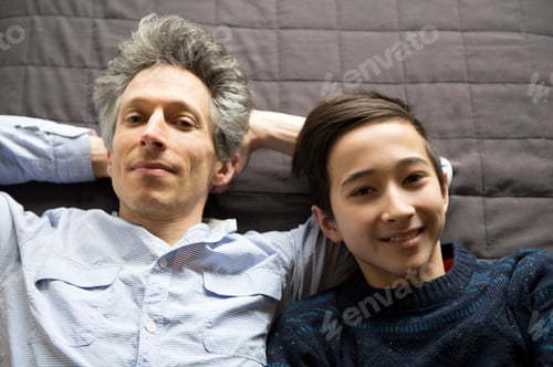 Preview: Overhead portrait of teenage boy and father lying back