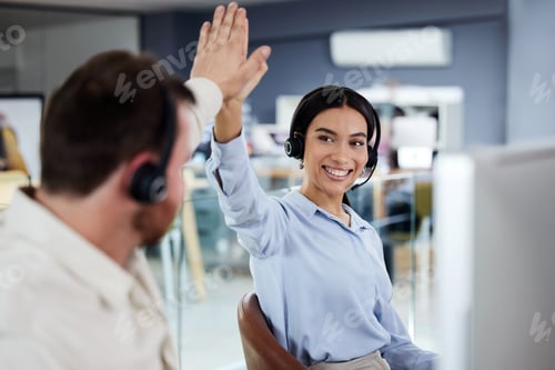 Preview: Shot of a young call centre agent sitting with a colleague in the office and giving him a high five
