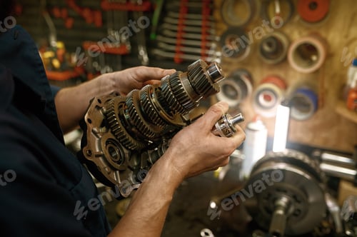 Preview: Motorcycle repair service indoor with closeup on serviceman hands holding gear