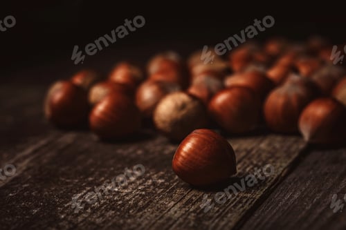 Preview: close up view of hazelnuts on wooden surface on black background