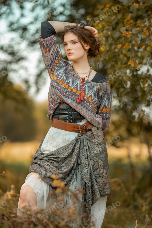 Preview: Young woman in boho style clothes posing in autumn forest