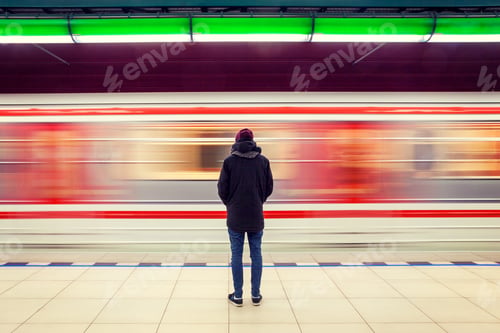 Preview: Lonely man from behind at subway station with moving train in background, motion blur