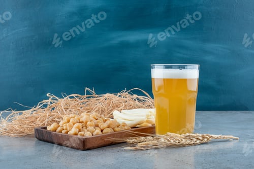 Preview: A wooden cutting board of peas and cheese with glass of beer