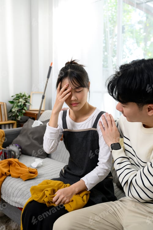 Preview: Tired asian couple resting on the couch after house cleaning