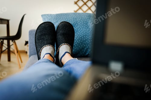 Preview: Lying on sofa in slippers with laptop working from home