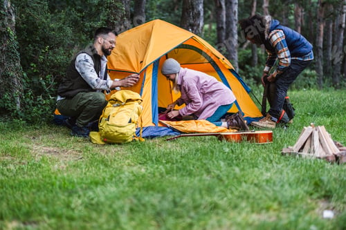 Preview: Friends setting up tent during camping trip in forest