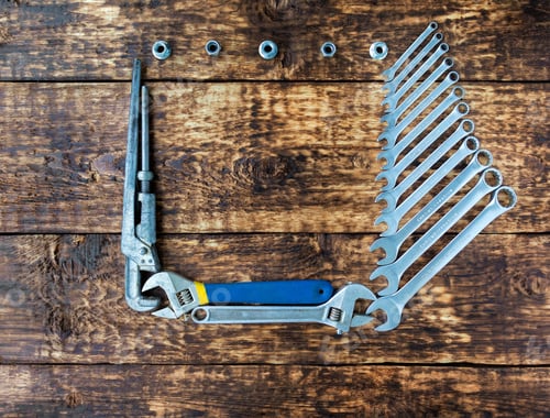 Preview: Set of combination and adjustable wrenches with a copy space in between, rustic wooden background