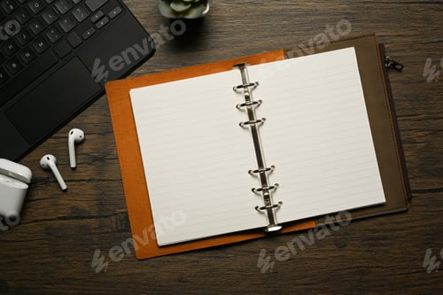 Preview: Top view of blank notebook, laptop and wireless earphones on wooden table