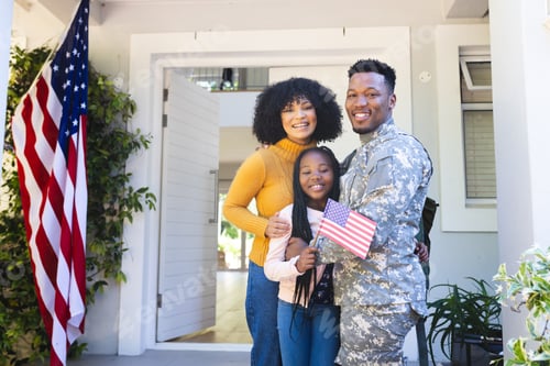 Preview: Portrait of happy african american family embracing outside home with usa flag, copy space
