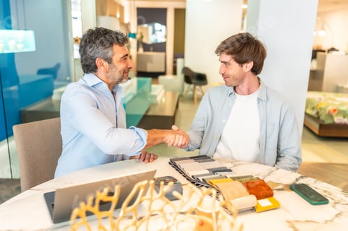 Preview: Interior designer shaking hands with client in furniture store showroom